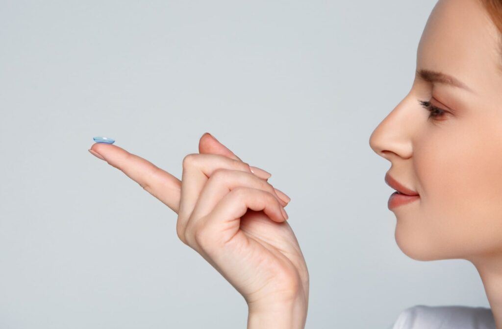 A woman holds a toric contact lens on her index finger in front of her face