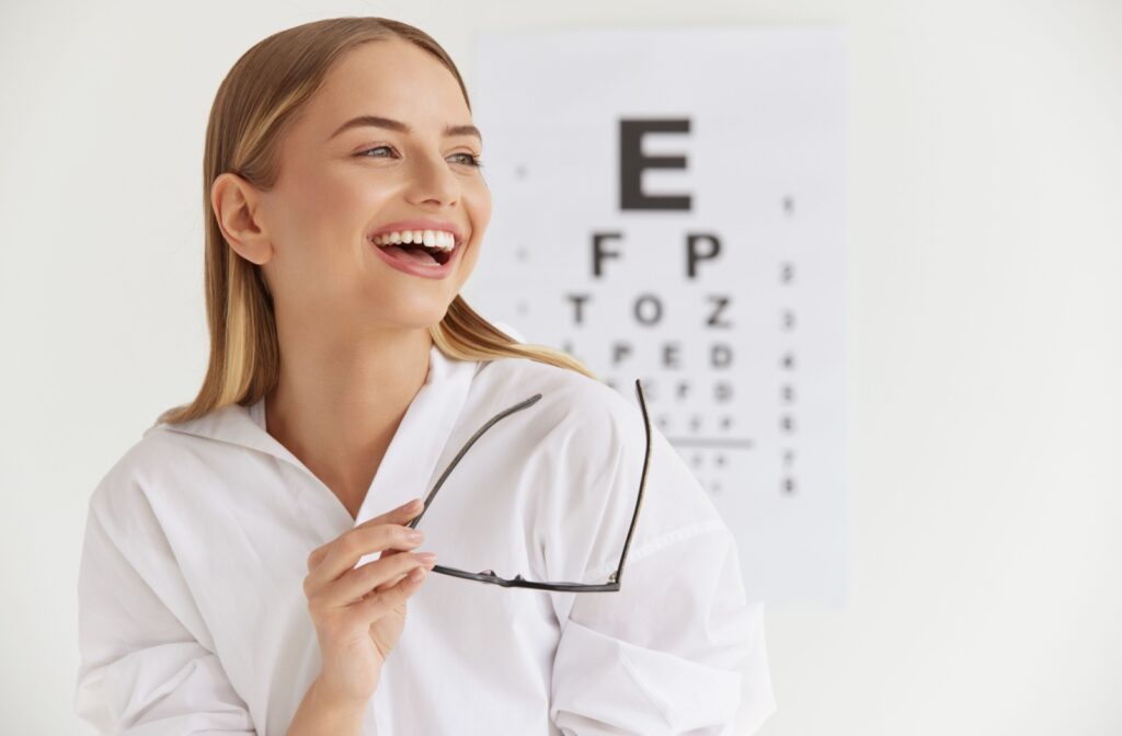 Smiling woman at optometrist office trying on new glasses after an eye exam