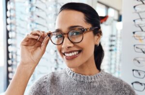 Woman trying on stylish glasses at optometrist office