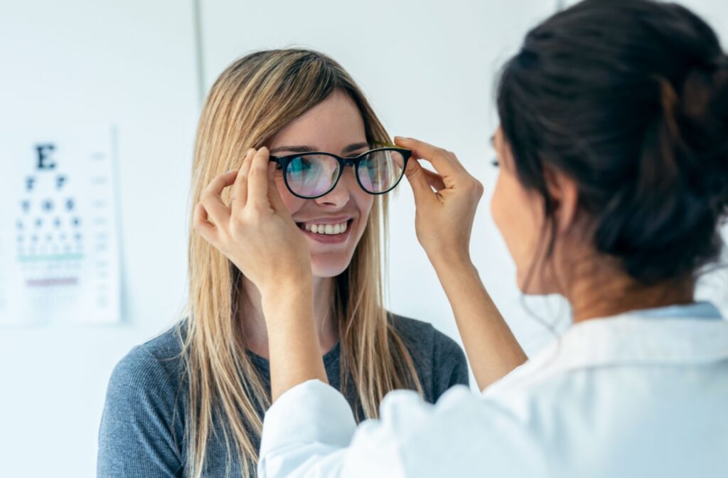 An optician helps a lady try on new eyeglasses.