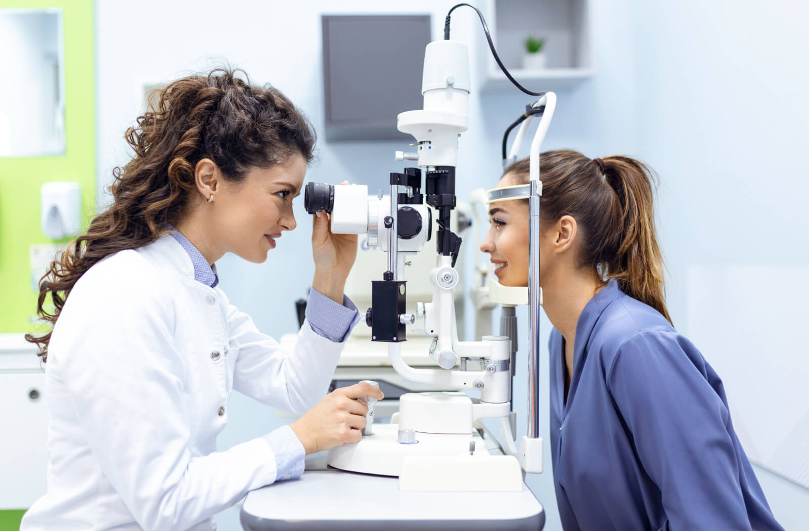 An optometrist examining a patient's eyes to diagnose her meibomian gland dysfunction.