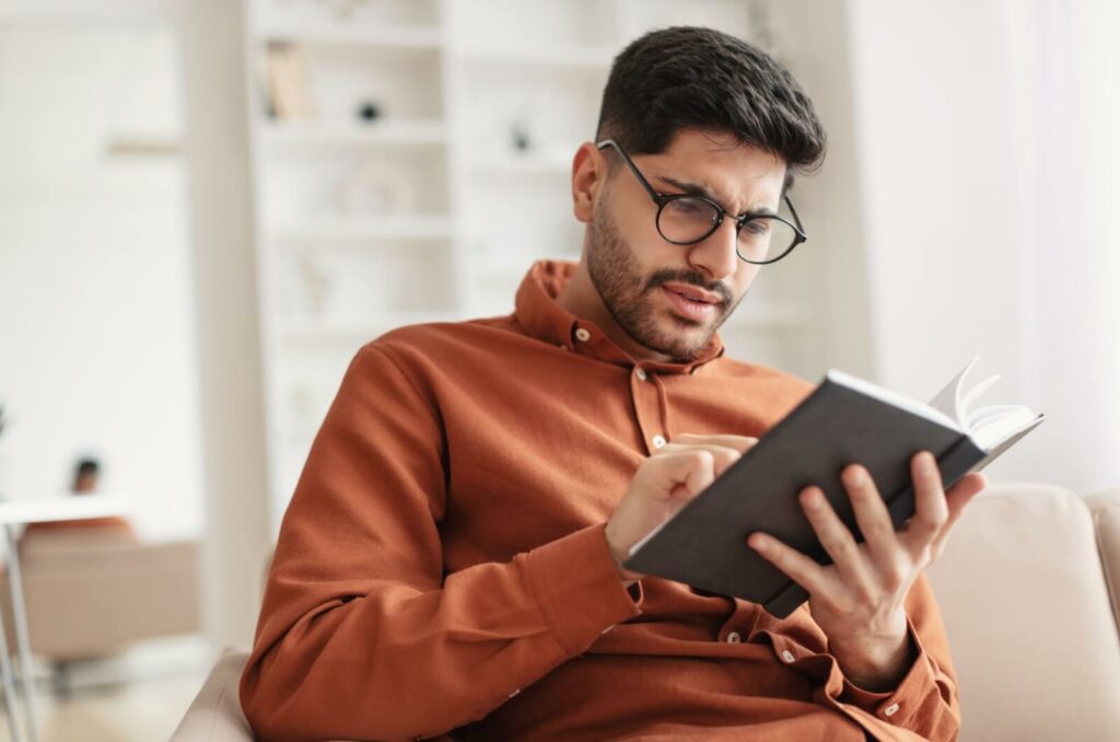 a young patient wearing glasses squints to read a book, experiencing blurred near vision